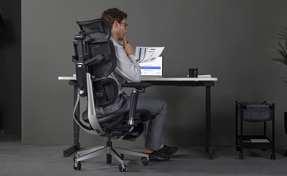 A_business_man_is_sitting_on_a_Hinomi_X2_Pro_ergonomic_chair_in_front_of_an_adjustable_office_desk.webp__PID:97484bbd-f129-4ad6-8936-210d49f4d925