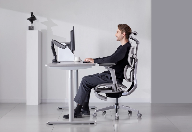 Man sitting in an ergonomic office chair at a desk with a computer, demonstrating proper posture and back support.